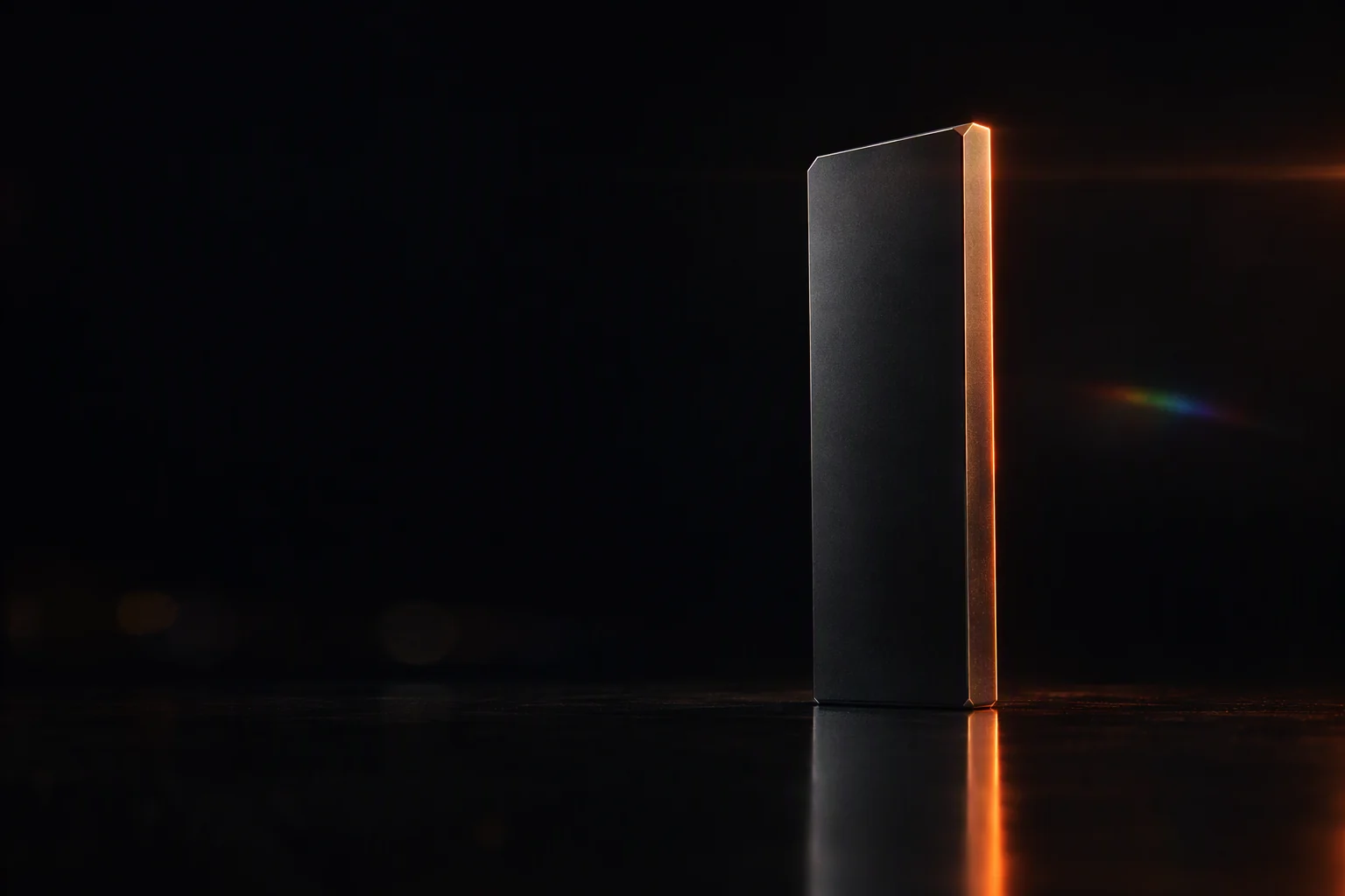 A dark bevelled metal monolith on a glossy black floor, its edge lit ember orange